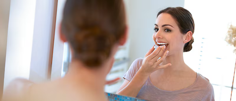 Lady using teeth whitening kit at home